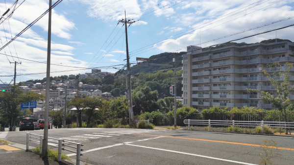 画面右には10階建くらいのマンション、その横には山の斜面に沿って家が階段上に立ち並んでいます。