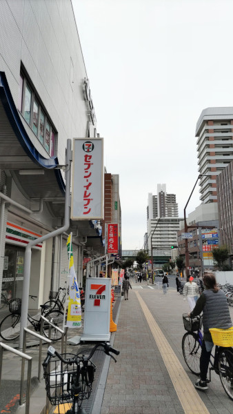 新長田駅をおりてすぐの大通り沿いの写真。右手にセブンイレブンが映っています。左手には背の高いビル群も。