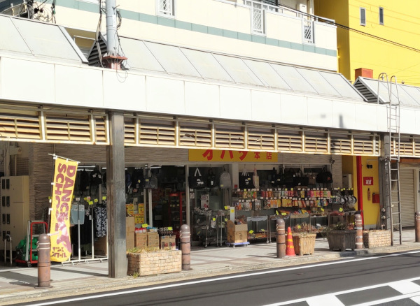 オバタ本店を左斜め前から撮影。店先に大きな旅行鞄や飲料などがたくさん並んでいて目を引きます。